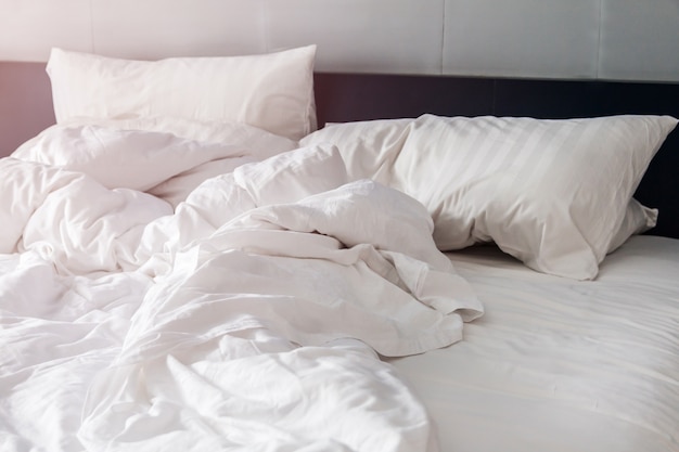 bed en witte kussens met rimpeldeken in de slaapkamer