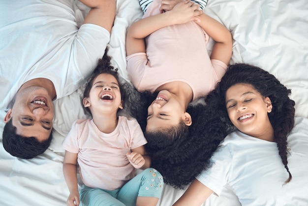 bed happy and above of parents and kids for relax rest and comfortable in morning family home and top view of mother father and children in bedroom for bonding relationship or laughing together