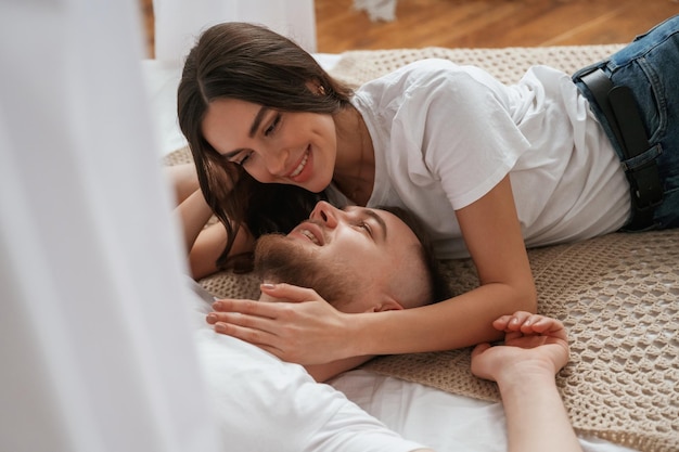 On the bed lying down and smiling Young couple are together at home