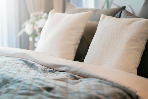 Bed maidup with clean white pillows and bed sheets in beauty room Closeup Lens flair in sunlightCloseup of new bed comforter with decorative pillows headboard in bedroom in staging model home