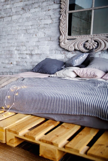 Foto bed met grijs beddengoed en kussens op houten pallets