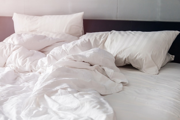 ベッドルームにシワブランケット付きのベッドと白の枕