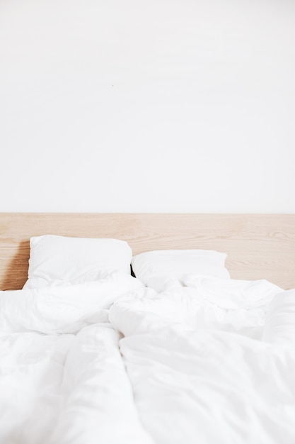 사진 깨끗한 흰색 리넨과 흰색 벽이있는 침대