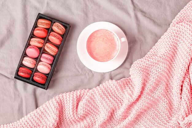 Bed with pink knitted plaid coffee and macaroons