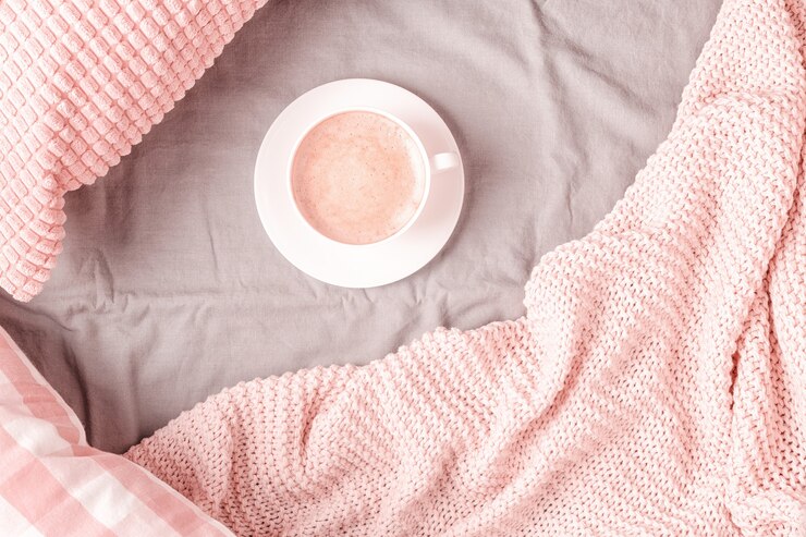 Bed with pink knitted plaid and coffee