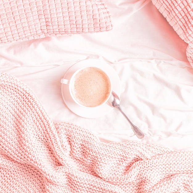 Bed with pink knitted plaid and coffee