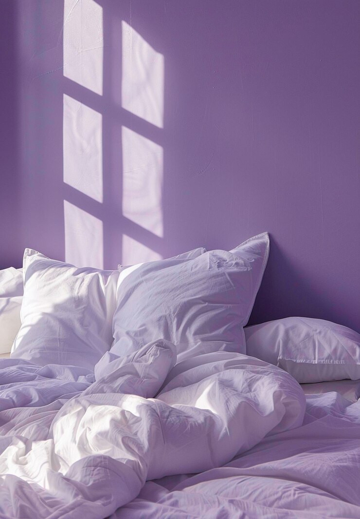 a bed with white sheets and a white pillow with the sun shining through the window