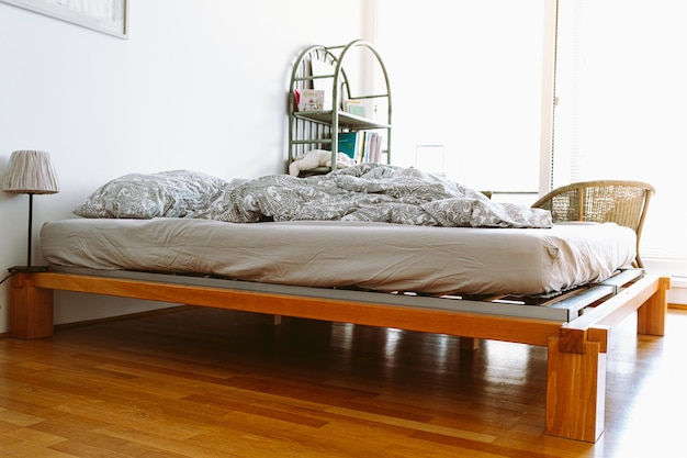 A bed with a wooden frame and a white wall behind it.