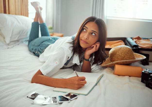 Bed woman thinking and writing in notebook for travel vacation adventure and photography memories in hotel bedroom Young girl relax and write traveling notes in journal or journey destination