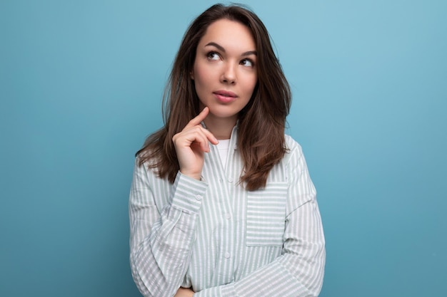 bedachtzame jonge brunette vrouw in hemd op achtergrond van de studio