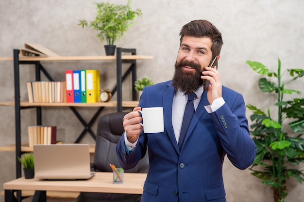 Bedankt voor het bellen Gelukkige man die aan de telefoon praat en thee drinkt Telefoongesprek op het werk Mobiel gesprek Zakelijk gesprek