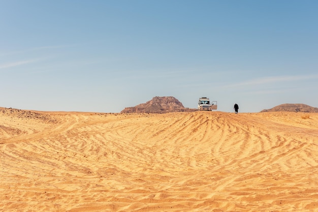 Bedoeïenen lopen naast de witte auto in de Sinaï-woestijn in Egypte
