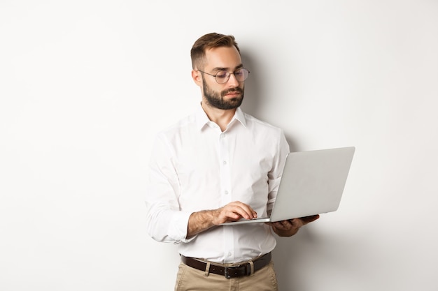 Bedrijf. Ernstige manager die aan laptop werkt, die zich over witte achtergrond bevindt