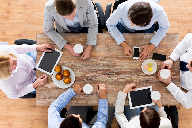 bedrijf, mensen, pauze en teamwerkconcept - close-up van creatieve teamvergadering en koffie drinken met muffins tijdens de lunch op kantoor