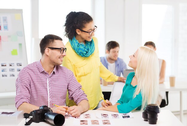 bedrijf, onderwijs, fotografie, kantoor en startup concept - glimlachend creatief team met afgedrukte foto's die op kantoor werken