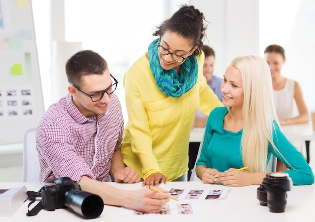 bedrijf, onderwijs, fotografie, kantoor en startup concept - glimlachend creatief team met afgedrukte foto's die op kantoor werken