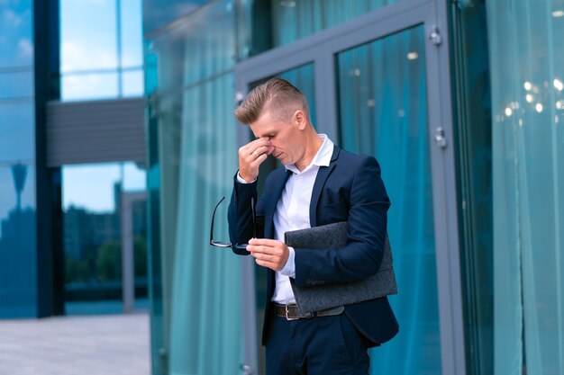 Bedrijf. zakenman, bril, met, map, staand, kantoorgebouw, ingang, zorgen, crisis, huilen, wrijft ogen, kaukasisch, mannelijke, zakenman, stad, corporatieve, gebouw, achtergrond, probleem, depressie, failliet