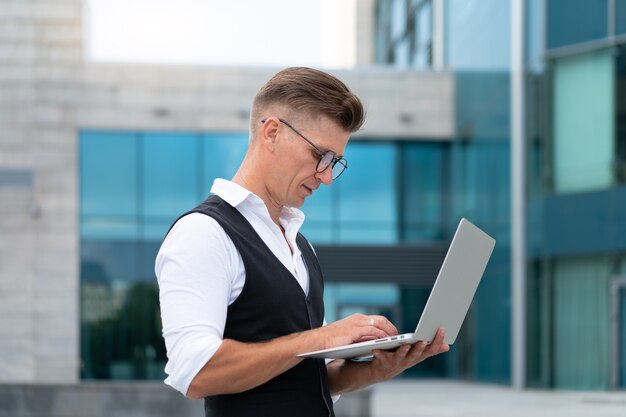 Bedrijf. zakenman met behulp van laptop buiten volwassen blanke mannelijke zakenman eyeglelesses kijken notebook scherm buiten serieus denken sulnlight achtergrond grote stad straat