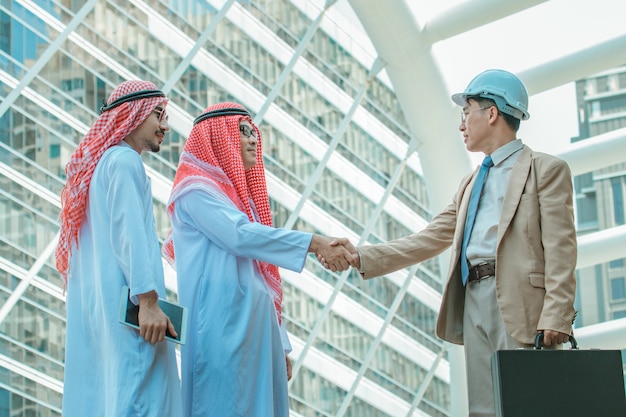 Bedrijfs- en kantoorconcept - Arabische en zakenman schudden de hand op stadsgezicht achtergrond