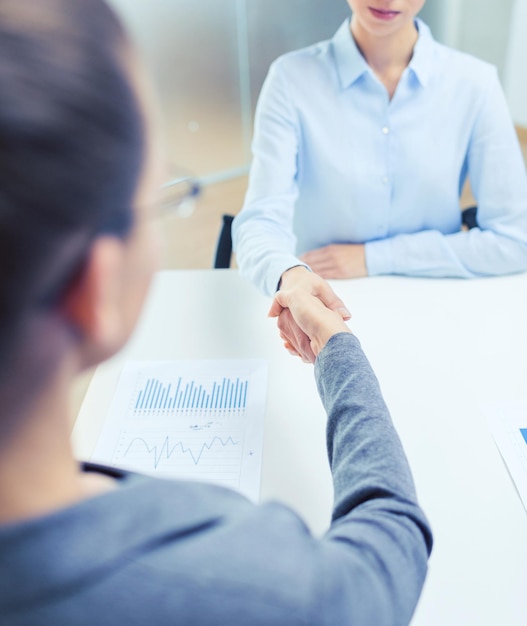 bedrijfs- en kantoorconcept - twee rustige zakenvrouwen die elkaar de hand schudden