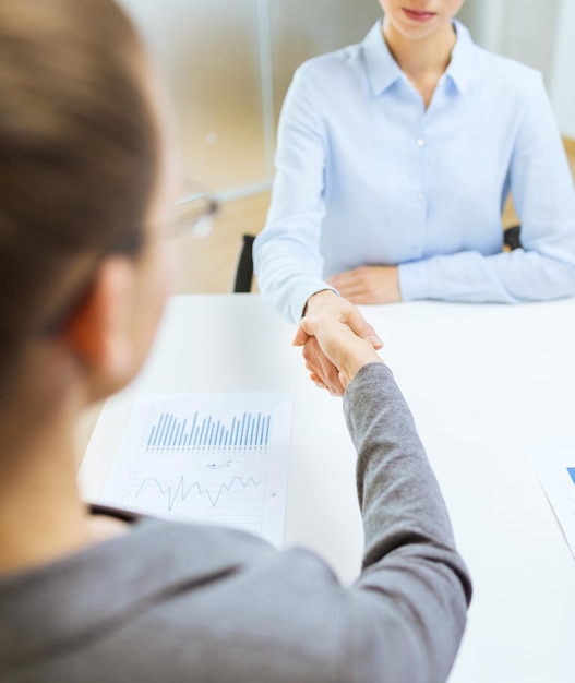 bedrijfs- en kantoorconcept - twee rustige zakenvrouwen die elkaar de hand schudden