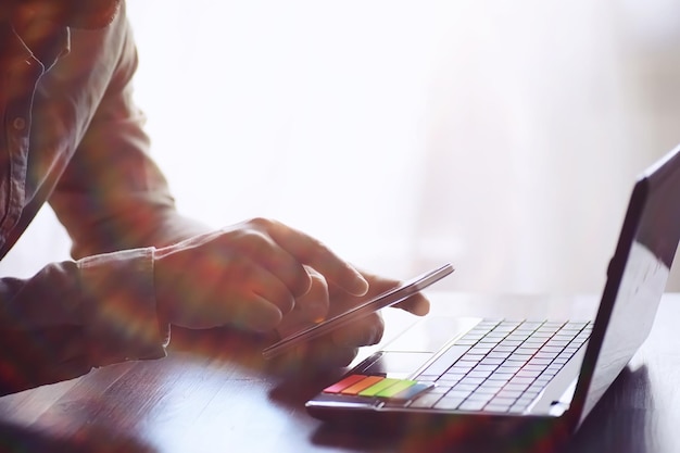 Bedrijfs- en technologieconcept Nadenkend casual zakenman freelancer programmeur met behulp van slimme mobiele telefoon terwijl hij aan een laptop werkt en nadenkt over zijn project in een modern kantoor close-up