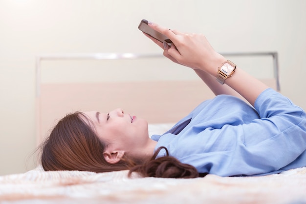 Bedrijfs en technologieconcept Vrouw die op bed ligt en aan mobiel werkt.