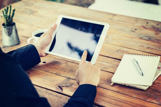 Bedrijfs man hand houden en gebruiken tablet op tafel in de koffiewinkel met vintage getinte filter.