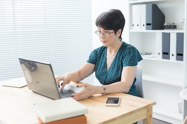 Bedrijfs-, mensen- en technologieconcept - vrouw van middelbare leeftijd met laptop die thuis werkt of