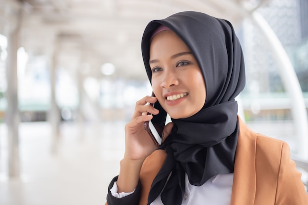Bedrijfs moslimvrouw die telefoon in stad met behulp van.