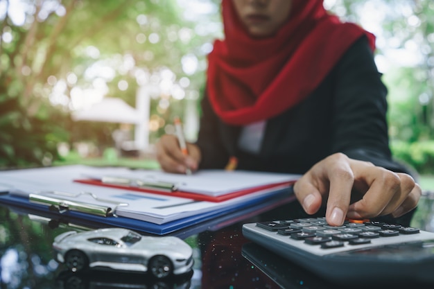 Bedrijfs moslimvrouwen handen die en autoverzekeringscitaten schrijven berekenen