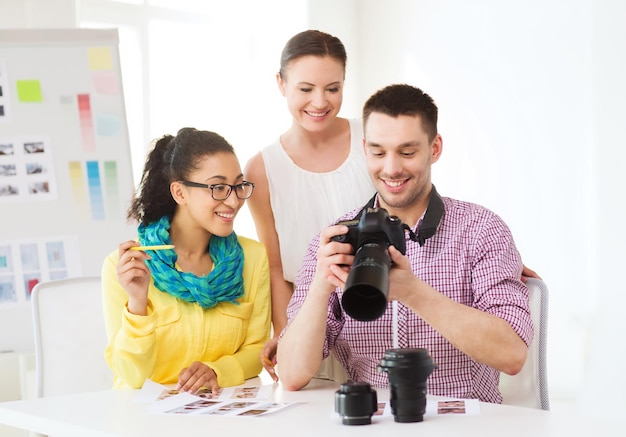 bedrijfs-, onderwijs-, kantoor- en startup-concept - glimlachend creatief team met fotocamera die op kantoor werkt