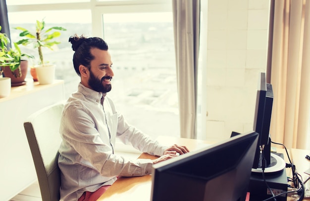 Bedrijfs-, start- en mensenconcept - gelukkige zakenman of creatieve mannelijke beambte met computer