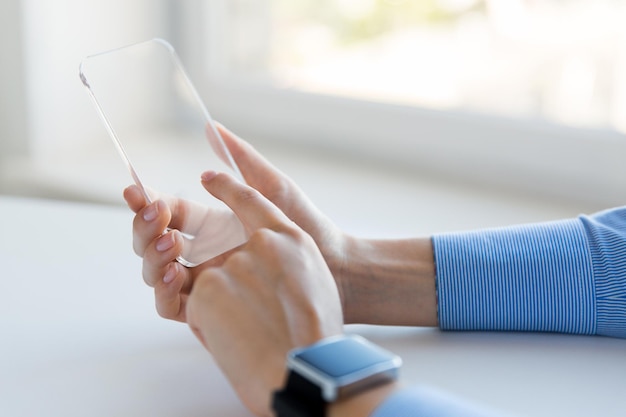 bedrijfs-, technologie- en mensenconcept - close-up van vrouwenhand die transparante smartphone en horloge op kantoor vasthoudt en toont
