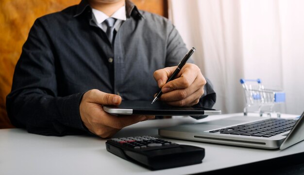 Bedrijfsboekhoudconcept Zakenman met rekenmachine met computerlaptopbudget en leningpapier op kantoor