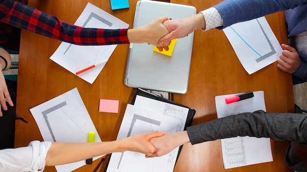 Bedrijfsconcept Mensen aan tafel begroeten elkaar met een handdruk