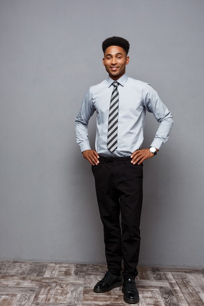 Bedrijfsconcept - Volledig lengteportret van zelfverzekerde Afro-Amerikaanse zakenman in het kantoor.