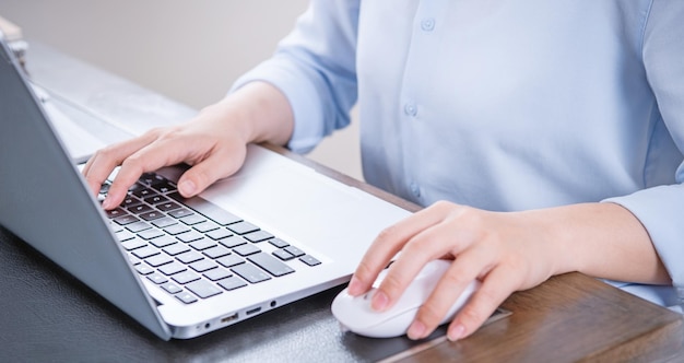 Bedrijfsconcept vrouw in blauw shirt typen op computer met koffie op kantoor tafel achtergrondverlichting zon schittering effect close-up zijaanzicht kopie ruimte