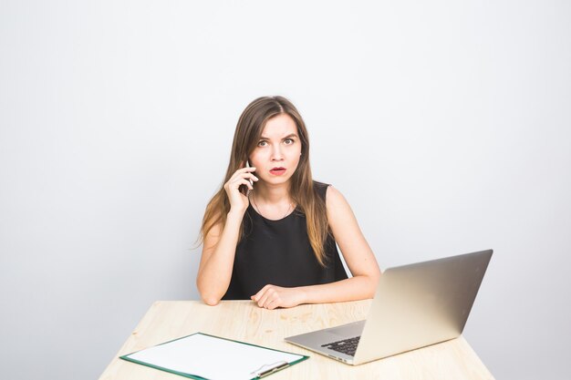 Bedrijfsconcept - zakenvrouw praten aan de telefoon in kantoor en werken op laptop.