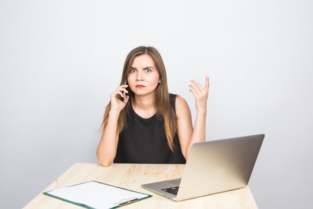 Bedrijfsconcept - zakenvrouw praten aan de telefoon in kantoor en werken op laptop.