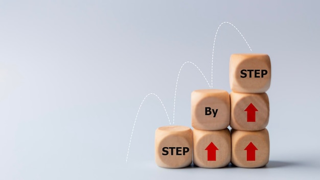 Bedrijfsconceptbeeld met houten blokjes woord stap voor stap op houten blokjes Prestatie of vooruitgang in de zakelijke carrière