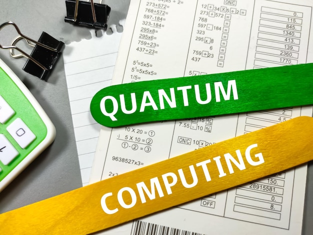 Foto bedrijfsconcepttekst quantum computing schrijven op gekleurde ijsstokjes met paperclipscalculator en document berekenen op grijze achtergrond