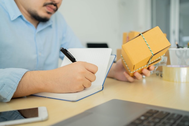 Foto bedrijfseigenaar zit thuis op de tafel terwijl hij details van de bestelling van de klant schrijft