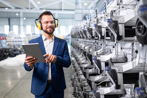 Bedrijfsmanager loopt langs de machine van de productielijn en controleert de productiviteit