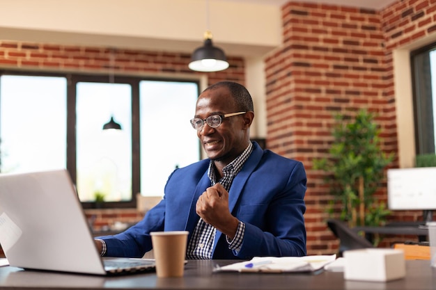 Bedrijfsmedewerker balde vuist om zakelijke prestatie op het werk te vieren. Gelukkige ondernemer die zich gelukkig en tevreden voelt na de marketingoverwinning en prestatie in het opstartkantoor.