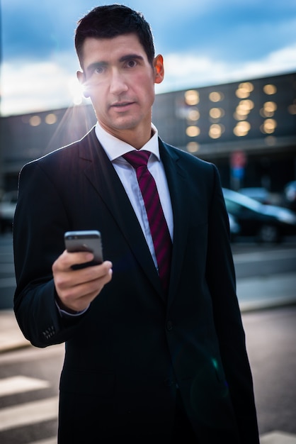 Bedrijfsmens die bij avond in openlucht texting