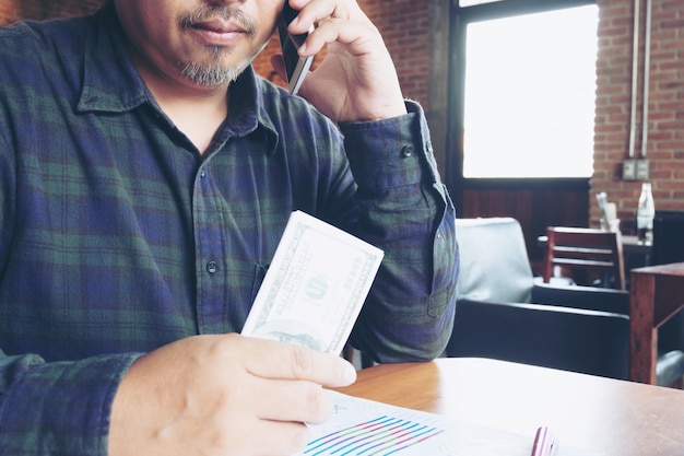 Bedrijfsmens die op Mobiele Telefoon spreken en Dollar in Hand houden