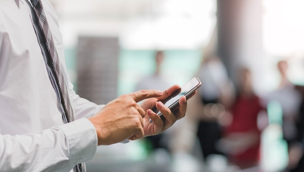 Bedrijfsmens die slimme telefoon op bureau ruimteachtergrond en exemplaarruimte met behulp van.