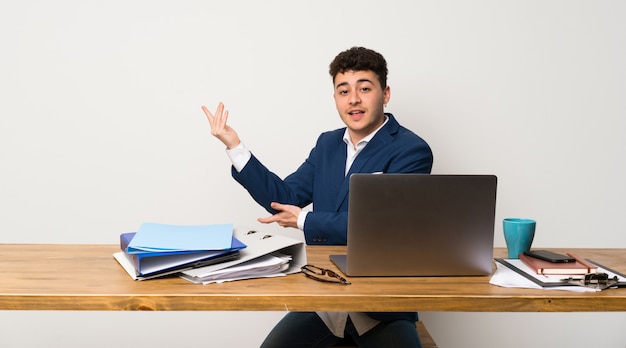 Bedrijfsmens in een bureau die handen uitbreiden aan de kant voor het uitnodigen om te komen