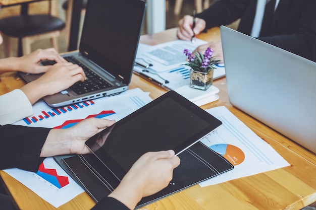 Bedrijfsmensen die bij het werken met financiële rapporten en een tablet samenkomen.